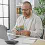 a man sitting at his laptop with Australian cash in his hands
