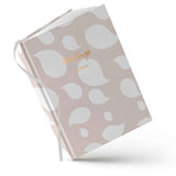 Notebook with white leaf pattern on a light pink background