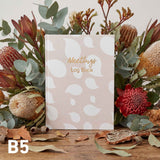 Meetings log book with floral arrangement on a wooden surface